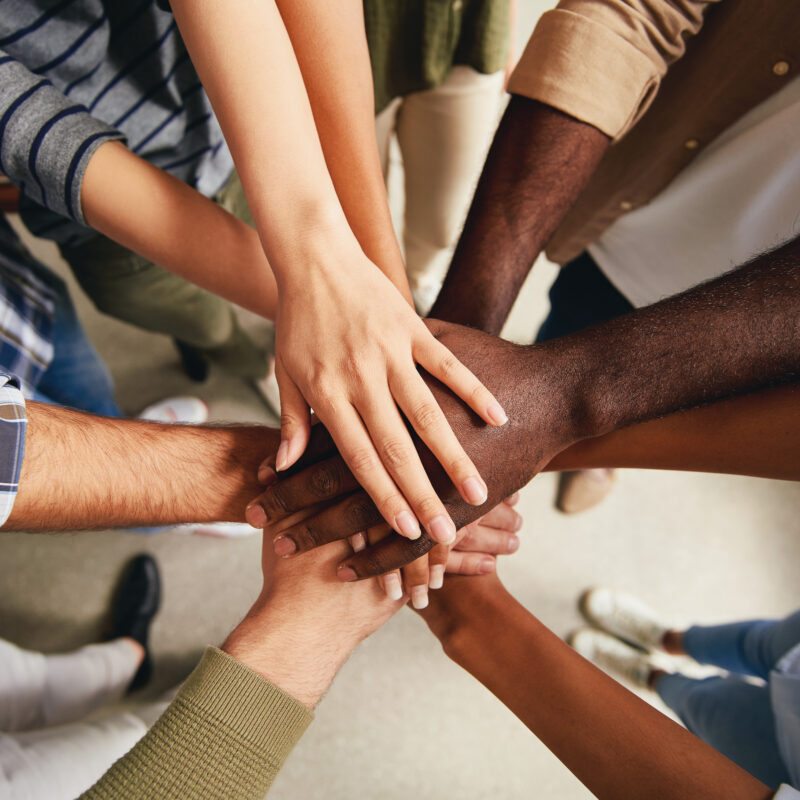 Cropped photo of multiracial people hands put on top of each other symbolizing unity